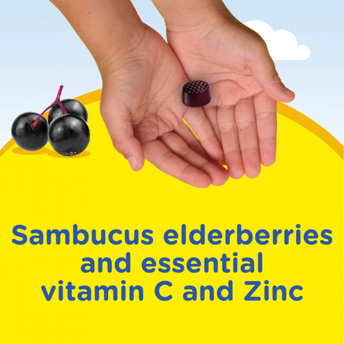 A child's hands hold an elderberry gummy from Kids Elderberry Complex, surrounded by fresh elderberries.