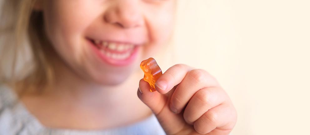 Young blonde girl is excited to eat gummy vitamin.