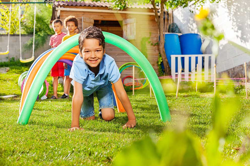 Kids crawl under barriers in an obstacle course as part of an exercise for kids.